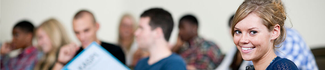 Startfoto DAJEB Frau sitzt in einer Gruppe und schaut nach vorne